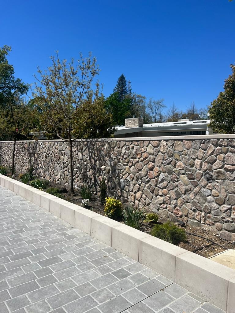 Mexican River Rock — exterior stone retaining wall with paved driveway